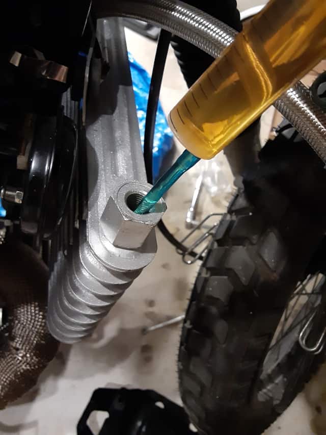 Filling motorcycle cooler with fresh oil using syringe.  