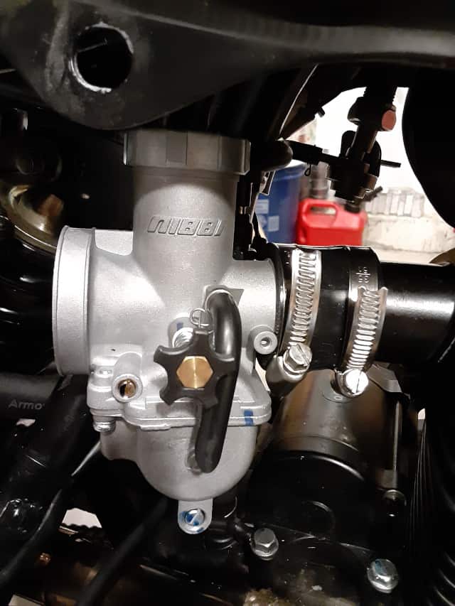 Nibbi carburetor installed with hose clamps installed.