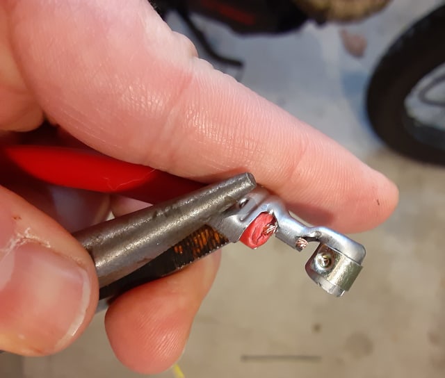 Crimping spark plug wire terminal to spark plug wire jacket.