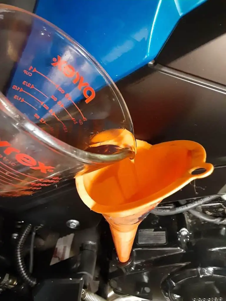 Filling oil with measuring cup.