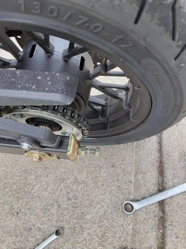 Motorcycle rear axle tensioner lock nut loosened.