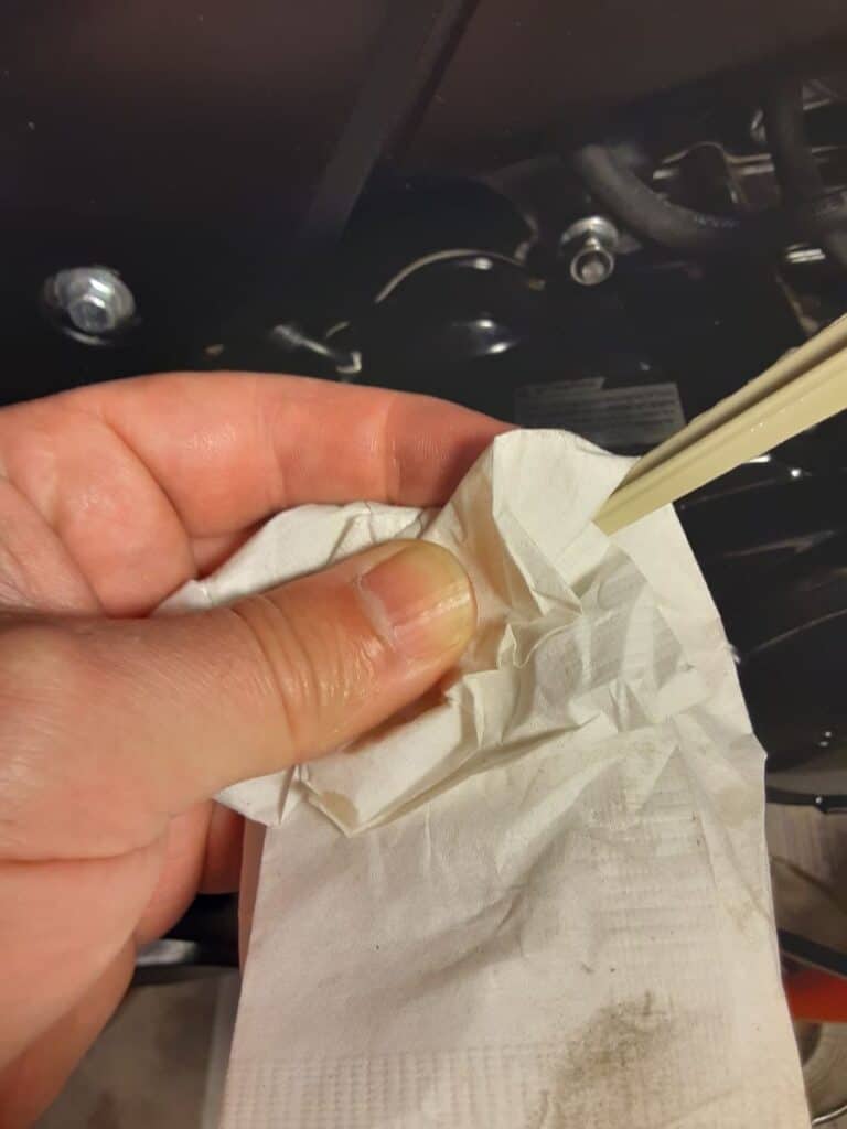 White paper towel wiping off dip stick and check motorcycle oil's condition.