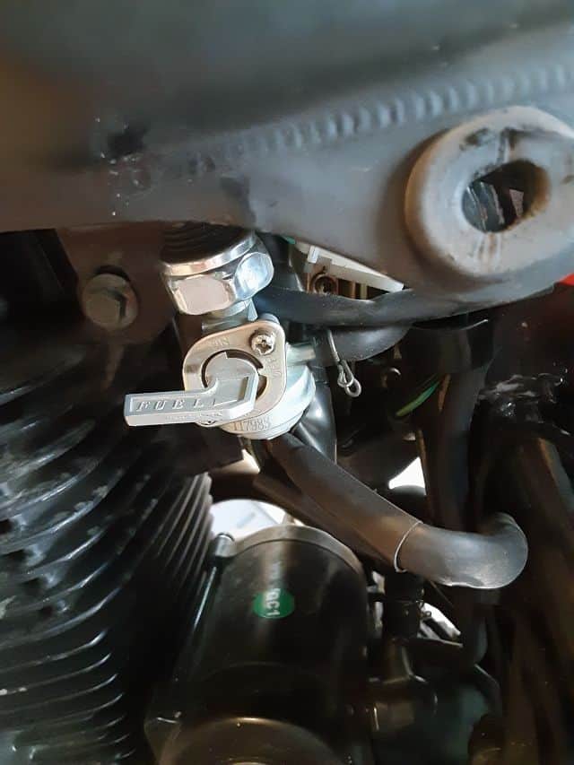 Hose spring clamp to right of fuel shut off valve.
