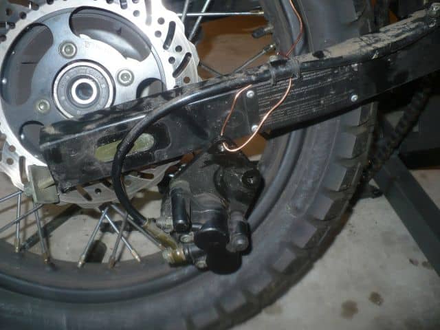Hanging rear brake caliper with wire.