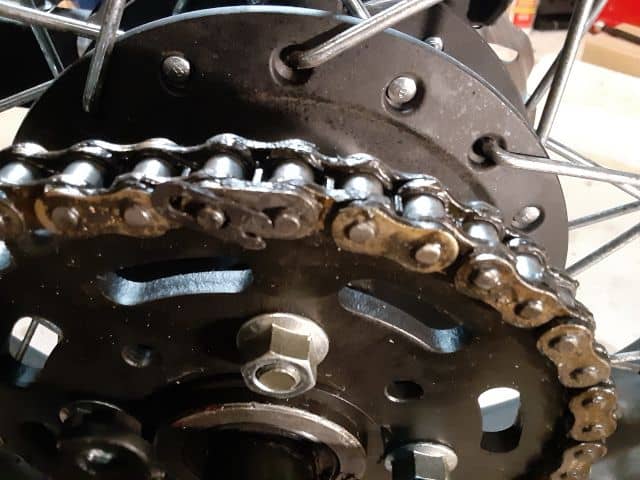 Motorcycle chain master link locking clip unsnapped.  Ready for removal.