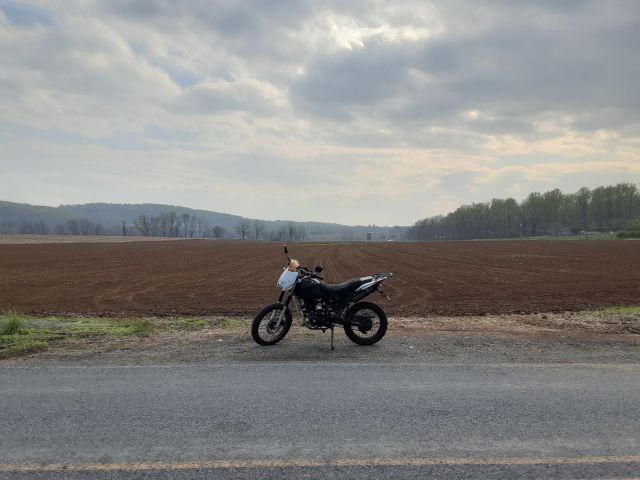 TaoTao TBR7 motorcycle in front of dirt of plowed farm field. 