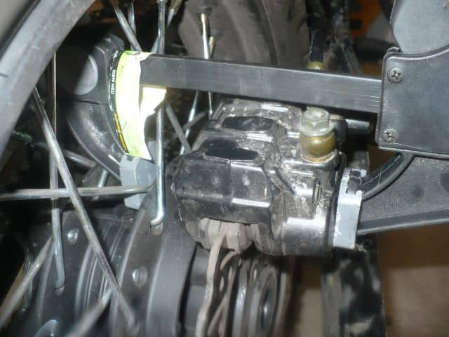 Compressing rear brake caliper with clamp.