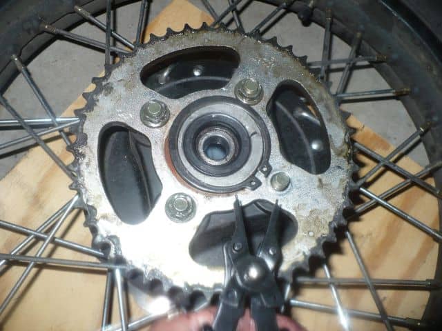 Removing TBR7 motorcycle rear hub snap ring with snap ring pliers.