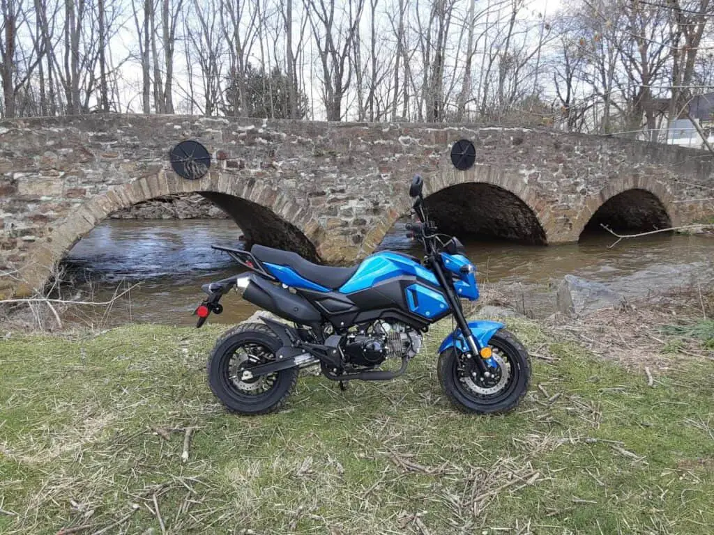 Boom Vader Gen 2 125cc motorcycle before reliability upgrades, in front of stone bridge.